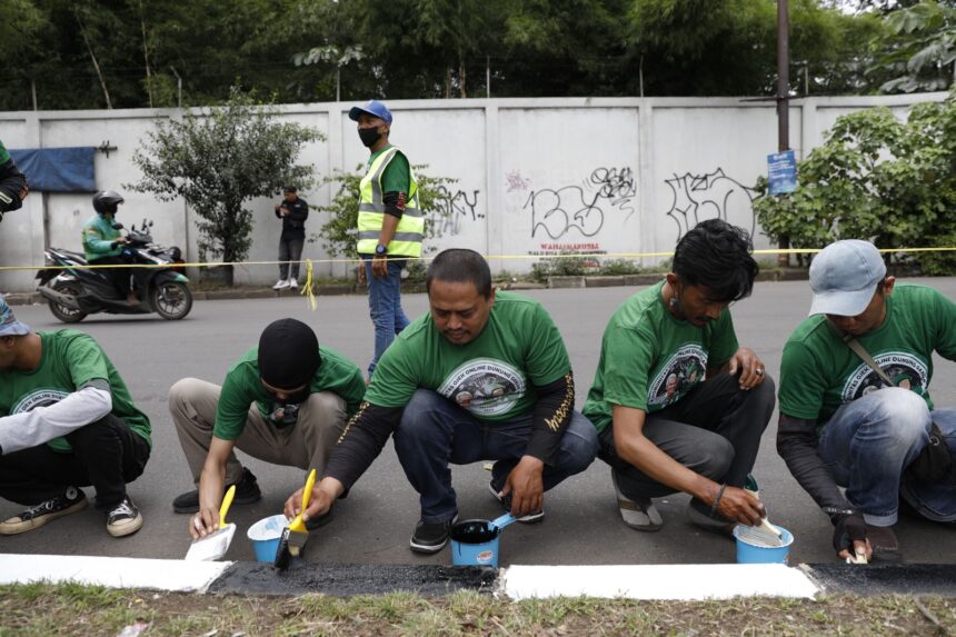 Komunitas Ojek Online (Ojol) atau Kajol Indonesia Dukung Ganjar Kabupaten Bogor melakukan aksi pengecatan separator dan bersih-bersih di Jalan Raya Mayor Oking Atmaja, Cibinong, Kabupaten Bogor, Jawa Barat, Rabu (15/2). Foto: Kajol