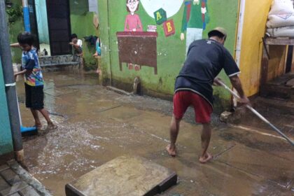 Pascabanjir, warga Kebon Pala, RW 04 dan RW 05, Kampung Melayu,​ Jatinegara, Jakarta Timur, membersihkan sisa lumpur tebal bercampur sampah di permukiman, Jumat (24/2) malam. Foto: Ist