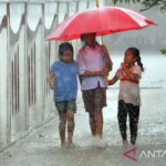 Tiga anak memakai payung untuk melindungi dirinya dari hujan, di Jakarta, Jumat (6/11/2022). FOTO ANTARA