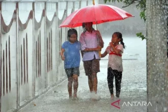 Tiga anak memakai payung untuk melindungi dirinya dari hujan, di Jakarta, Jumat (6/11/2022). FOTO ANTARA