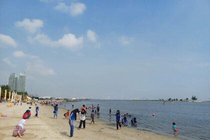 Para pengunjung asik bermain pasir putih dan juga berenang di sepanjang pantai Ancol, sambil menunggu matahari terbenam. Foto: Dok/ipol.id