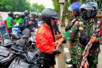 Dua personel TNI mengamankan tiga remaja yang membawa senjata tajam berukuran besar disembunyikan dalam kain sarung di Jalan Raya TMII, Makasar, Jakarta Timur. Foto: TNI