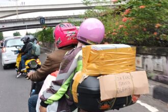 Pemudik roda dua melintasi Jalan Raya Kalimalang, Jatinegara, Jakarta Timur-Cawang. Di bagian belakang motor pemudik itu tertempel/diikat kardus bertuliskan jenaka dengan tulisan 'Jatakon Gawa Oleh-Oleh', Selasa (25/4) sore. Foto: Joesvicar Iqbal/ipol.id