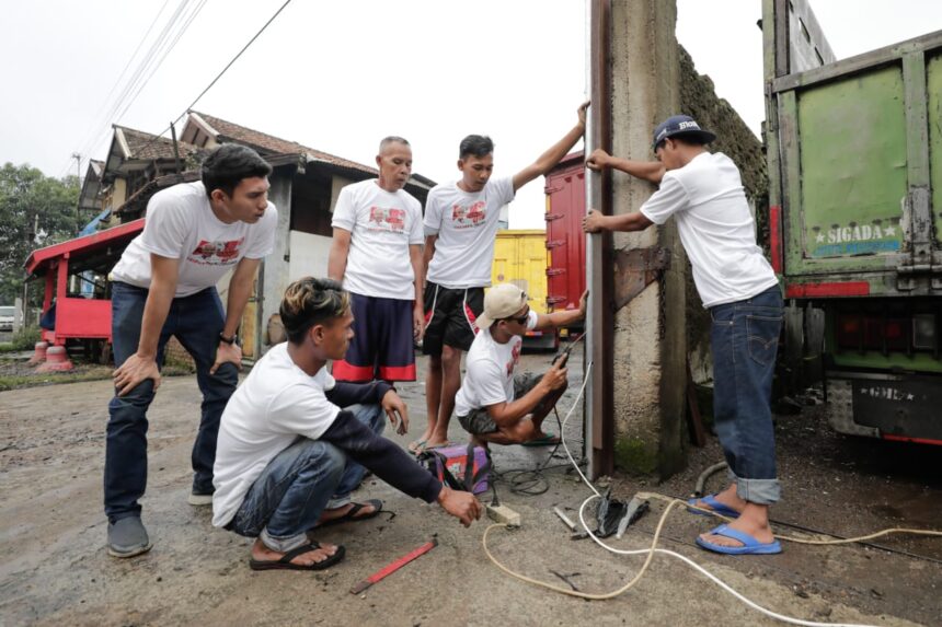Para sopir truk memasang tiga unit tiang lampu penerangan jalan dan beberapa unit lampu portable yang diberikan oleh Komunitas Sopir Truk (KST) Jawa Barat di pangkalan truk di kawasan Baleendah, Kabupaten Bandung,