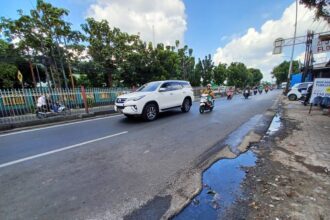 Belakangan ini hujan yang mengguyur wilayah Jakarta Timur kerap membuat Jalan Raya Bogor menjadi rusak dan berlubang, Jumat (12/5) siang. Para pengendara motor yang melintas berupaya menghindari jalan yang rusak dan berlubang. Foto: Joesvicar Iqbal/ipol.id