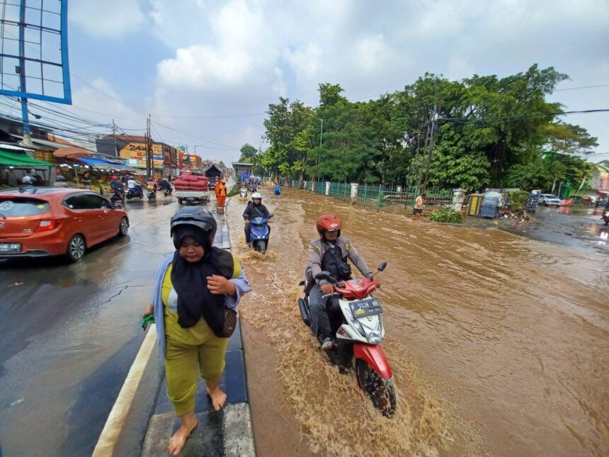 Para pengguna kendaraan bermotor berupaya menerabas banjir yang disebabkan meluapnya Kali Baru di Jalan Raya Bogor, Kramat Jati, Jakarta Timur, Senin (19/6) pagi. Foto: Joesvicar Iqbal/ipol.id