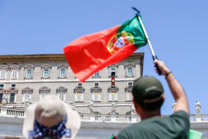 Seorang pria mengibarkan bendera Portugis saat Paus Fransiskus berdoa bersama para pengunjung yang berkumpul di Lapangan Santo Petrus di Vatikan pada Ahad (9/07/2023).