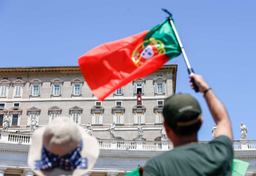 Seorang pria mengibarkan bendera Portugis saat Paus Fransiskus berdoa bersama para pengunjung yang berkumpul di Lapangan Santo Petrus di Vatikan pada Ahad (9/07/2023).