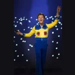 Harry Styles tampil dengan busana berwarna biru dan kuning.