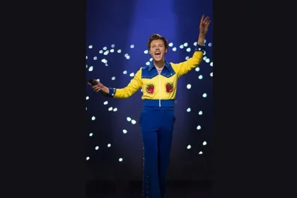 Harry Styles tampil dengan busana berwarna biru dan kuning.