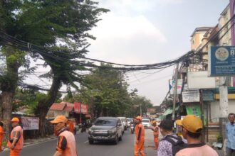 Sejumlah pasukan kuning dan PPSU merapikan kabel yang tersangkut kendaraan berat truk di Jl. H. Syaip, Gandaria Selatan, Cilandak, Jakarta Selatan, Senin (28/8). Foto: Ist