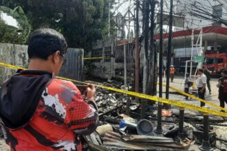 Aparat kepolisian memberikan garis police line pada kios tambal ban sekaligus penjual bensin eceran yang kebakaran di Jalan Raya Matraman, Kebon Manggis, Matraman, Jakarta Timur, pada Rabu (30/8) sekitar pukul 12.53 WIB. Foto: Ist