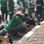 Komunitas Ojek Online (Kajol) Indonesia Jakarta Timur (Jaktim) mengecat separator yang sudah kusam di Jalan Pintu 2 Taman Mini, Kecamatan Cipayung, Selasa (22/8). Foto: Kajol