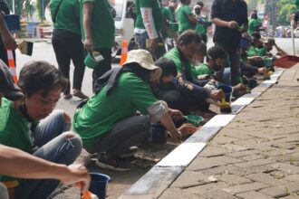 Komunitas Ojek Online (Kajol) Indonesia Jakarta Timur (Jaktim) mengecat separator yang sudah kusam di Jalan Pintu 2 Taman Mini, Kecamatan Cipayung, Selasa (22/8). Foto: Kajol
