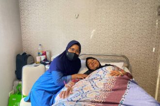 Ibu Asmajati (66) seorang peserta Program Jaminan Kesehatan Nasional (JKN) segmen Pekerja Penerima Upah (PPU) kelas rawat dua. Kala itu Ibu Asmajati sedang menjalani perawatan pasca operasi pengangkatan lipoma pada lehernya. Foto/dok/BPJS