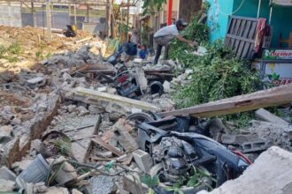 Sejumlah pekerja membersihkan puing reruntuhan yang menimpa empat unit motor dan tiga rumah yang rusak berat di Gang Anggrek, RT 05/RW 04, Kelurahan Klender, Kecamatan Duren Sawit, Jakarta Timur, Senin (25/9) siang tadi. Foto: Joesvicar Iqbal/ipol.id