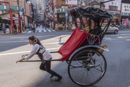 PEnarik becak perempuan saat mengantar dua orang penumpang perempuan di Asakusa, Tokyo.