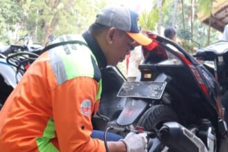 Seorang petugas Suku Dinas (Sudin) Lingkungan Hidup (LH) Kota Administrasi Jakarta Selatan melakukan uji emisi kendaraan roda dua milik warga di Kantor Kecamatan Tebet, Rabu (11/10). Foto: Ist