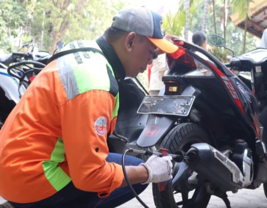 Seorang petugas Suku Dinas (Sudin) Lingkungan Hidup (LH) Kota Administrasi Jakarta Selatan melakukan uji emisi kendaraan roda dua milik warga di Kantor Kecamatan Tebet, Rabu (11/10). Foto: Ist