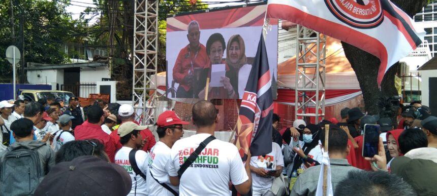 Massa pendukung pasangan capres-cawapres, Ganjar-Mahfud MD mendengarkan pidato Ketua Umum PDIP, Megawati lewat videotron di depan pagar gedung KPU RI.(foto Sofian/ipol.id)