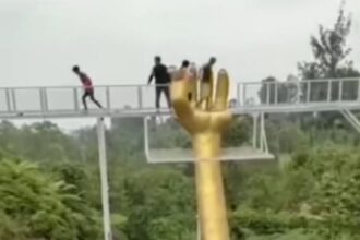 Pengelola membantu wisatawan menyebrangi jembatan kaca di Banyumas Jateng.