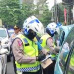 Aparat kepolisian melakukan penilangan terhadap kendaraan taksi biru yang parkir di bahu jalan di kawasan Cibubur, Jakarta Timur, beberapa waktu lalu. Foto: Dok/ipol.id