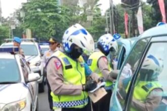 Aparat kepolisian melakukan penilangan terhadap kendaraan taksi biru yang parkir di bahu jalan di kawasan Cibubur, Jakarta Timur, beberapa waktu lalu. Foto: Dok/ipol.id