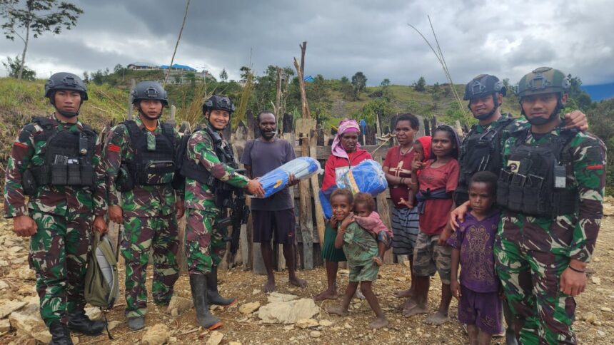 Prajurit Satgas 330 memberikan bantuan terpal untuk atap honai yang sedang dibangun oleh Martin, warga Intan Jaya, Papua. Foto: Ist