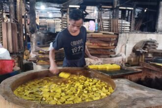 Salah satu pengrajin dari produsen tahu di Gang Nusa Indah, RT 01/RW 07, Kelurahan/Kecamatan Ciracas, Jakarta Timur, mengolah dan mengangkat tahu kuning yang sudah jadi hingga mengemasnya, Selasa (7/11). Foto: Joesvicar Iqbal/ipol.id