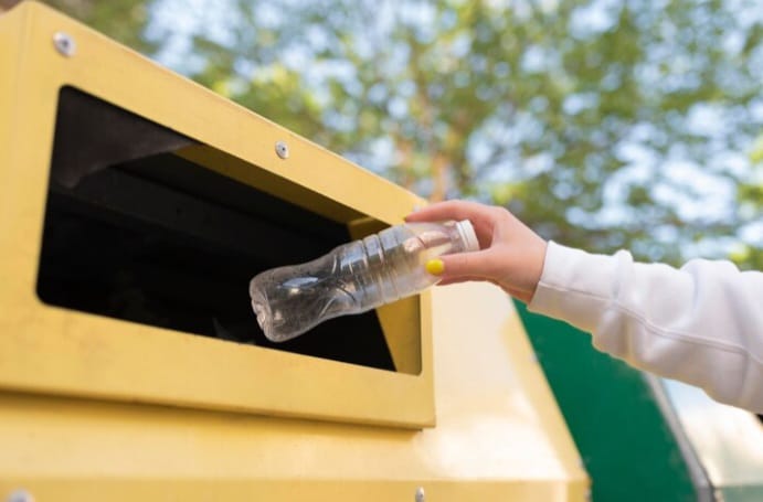 Ilustrasi - Warga membuang botol bekas air mineral ke dalam gerobak sampah untuk menjaga lingkungan tetap bersih. Foto: Freepik