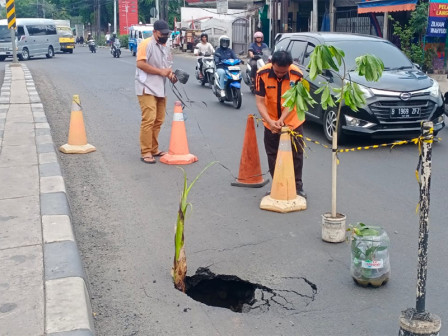 Keadaan saat aspal Jalan Raya Bogor, Kelurahan Susukan, Kecamatan Ciracas, yang ambles sebelum diperbaiki sejumlah petugas Sudin SDA dan Sudin Bina Marga Jakarta Timur, Selasa (21/11). Petugas Satpol PP dan PPSU mengatur arus lalu lintas serta memasang rambu. Foto: Ist