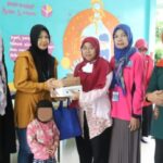 Sekretaris Kelurahan Jagakarsa, Zubaidah saat menyerahkan bantuan paket Pemberian Makanan Tambahan (PMT) kepada para Ibu dari balita terduga stunting di Ruang Publik Terpadu Ramah Anak (RPTRA) Beringin, Jagakarsa, Jakarta Selatan, Jumat (1/12).