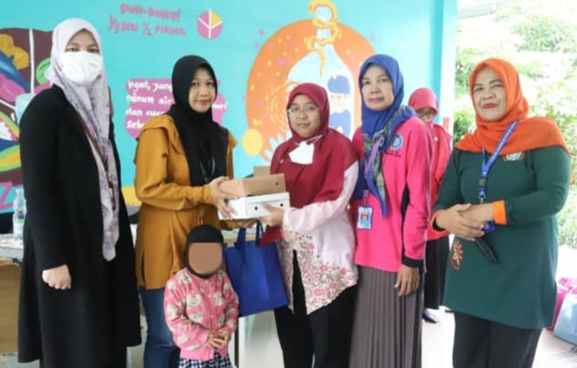Sekretaris Kelurahan Jagakarsa, Zubaidah saat menyerahkan bantuan paket Pemberian Makanan Tambahan (PMT) kepada para Ibu dari balita terduga stunting di Ruang Publik Terpadu Ramah Anak (RPTRA) Beringin, Jagakarsa, Jakarta Selatan, Jumat (1/12).