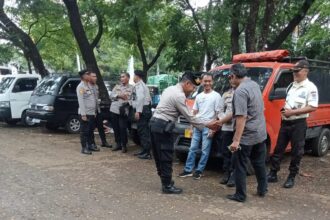 Puluhan aparat kepolisian dari Polres Metro Jakarta Timur dan Polsek Kramat Jati melakukan penjagaan di lahan parkir di pasar sayur mayur terbesar di Pasar Induk Kramat Jati, Rabu (6/12). Foto: Ist