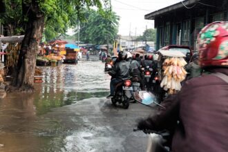 Para pengendara motor dan mobil antri melintasi genangan di Jalan Raya Bogor, Kecamatan Kramat Jati, Jakarta Timur pada Senin (25/12) pagi. Foto: Joesvicar Iqbal/ipol.id