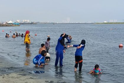 Para pengunjung, keluarga dan anak-anak menikmati bermain pasir putih di bibir pantai Ancol Taman Impian Jakarta. Foto: Dok/ipol.id