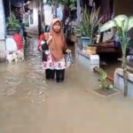 Seorang Ibu warga di Jalan Cipinang Bali, Cipinang Muara, Jatinegara, Jakarta Timur, Rabu (31/1), berjalan menerabas banjir untuk melakukan aktivitas keseharian. Foto: Joesvicar Iqbal/ipol.id
