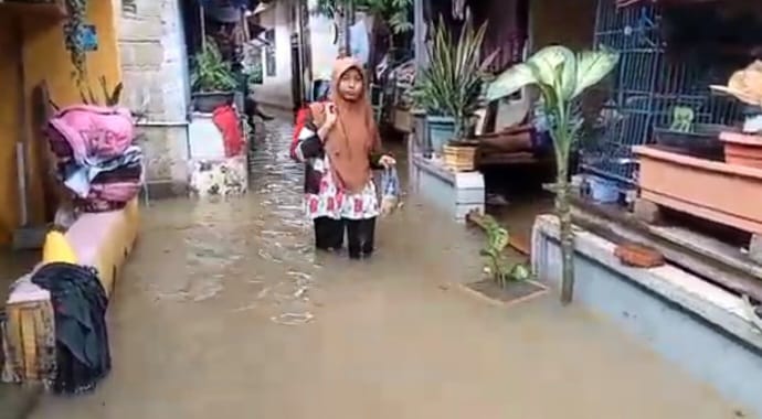 Seorang Ibu warga di Jalan Cipinang Bali, Cipinang Muara, Jatinegara, Jakarta Timur, Rabu (31/1), berjalan menerabas banjir untuk melakukan aktivitas keseharian. Foto: Joesvicar Iqbal/ipol.id