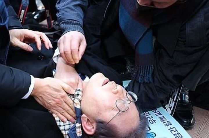 Lee Jae-myung, pemimpin oposisi utama Partai Demokrat, berbaring setelah diserang oleh penyerang di sisi kiri lehernya saat berkunjung ke lokasi pembangunan bandara di Pulau Gadeok di lepas pantai tenggara kota pelabuhan Busan pada 2 Januari 2024. Foto: Yonhap