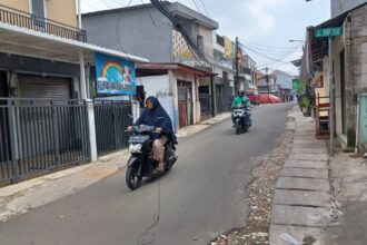 Suasana sejumlah pengguna jalan pengendara sepeda motor menghindari kabel yang menjuntai di Jalan Cibubur II, Blok Dukuh, Kelurahan Cibubur, Kecamatan Ciracas, Jakarta Timur, Selasa (20/2) siang. Foto: Joesvicar Iqbal/ipol.id