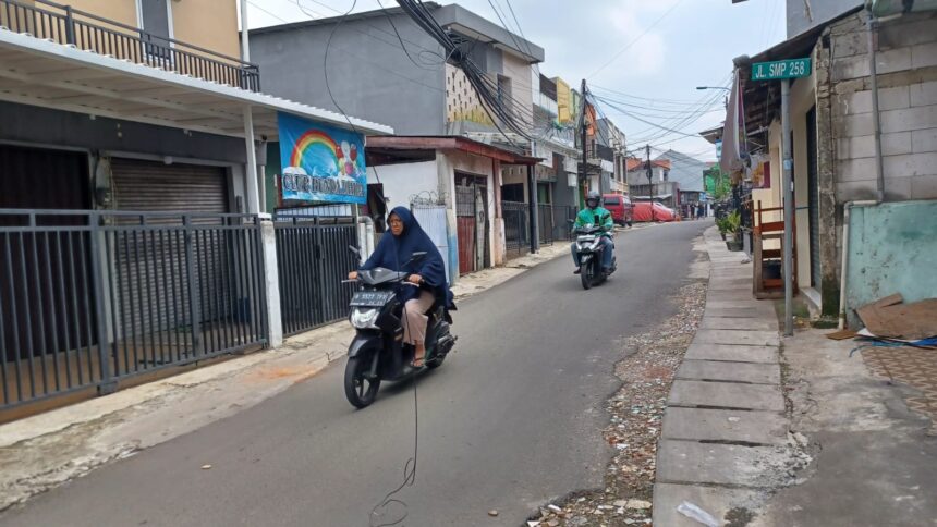 Suasana sejumlah pengguna jalan pengendara sepeda motor menghindari kabel yang menjuntai di Jalan Cibubur II, Blok Dukuh, Kelurahan Cibubur, Kecamatan Ciracas, Jakarta Timur, Selasa (20/2) siang. Foto: Joesvicar Iqbal/ipol.id