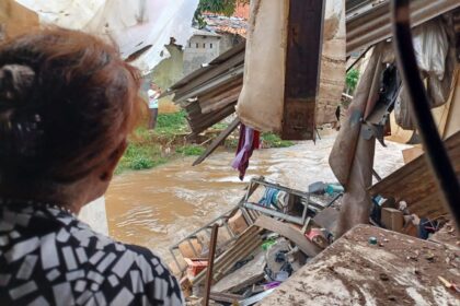 Pemilik bengkel 'Cibubur Jaya Motor' Herti, 66, syok usai kejadian longsor dialaminya, duit dan tasnya terseret aliran Kali Baru di Jalan Raya Bogor Km 27, No 4, Cibubur, Jakarta Timur, Senin (26/2) siang. Foto: Joesvicar Iqbal/ipol.id