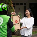 Driver Gojek mengantarkan pesanan makanan (gofood) kepada seorang pelanggan di rumahnya. Foto: Ist