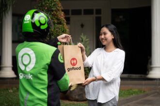 Driver Gojek mengantarkan pesanan makanan (gofood) kepada seorang pelanggan di rumahnya. Foto: Ist
