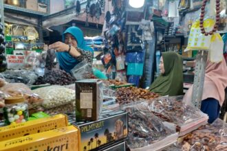 Pedagang kurna yakni Elawati yang juga pemilik Toko KK di Jalan Pasar Utara Jatinegara, Jakarta Timur, saat melayani pembeli kurma, Senin (11/3) siang. Foto: Joesvicar Iqbal/ipol.id