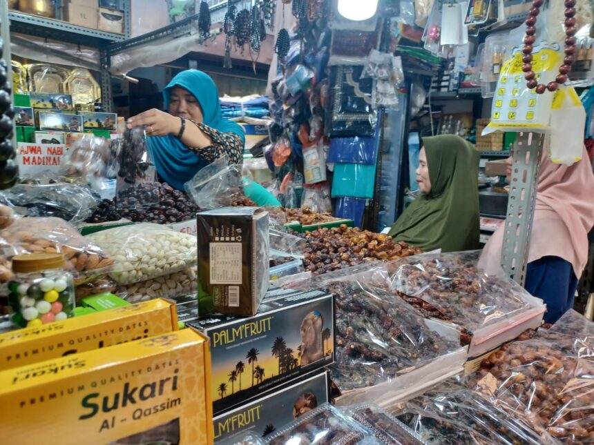 Pedagang kurna yakni Elawati yang juga pemilik Toko KK di Jalan Pasar Utara Jatinegara, Jakarta Timur, saat melayani pembeli kurma, Senin (11/3) siang. Foto: Joesvicar Iqbal/ipol.id