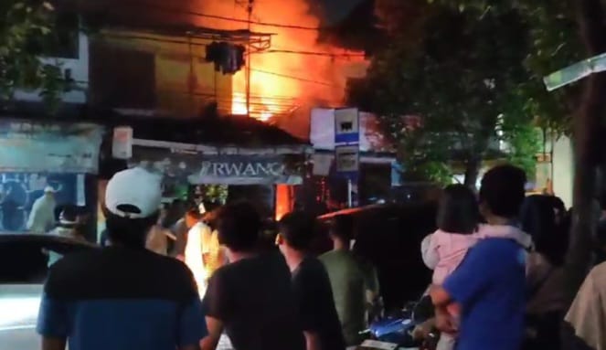 Suasana saat warga sekitar menyaksikan gerai restoran makanan siap saji di Jalan Haji Naman, Kelurahan Pondok Kelapa, Kecamatan Duren Sawit, Jakarta Timur, kebakaran pada Selasa (12/3) malam. Foto: Ist