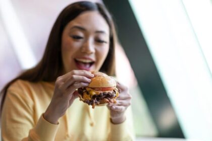 Ilustrasi - Seorang perempuan cantik sedang menikmati roti isi ketika masuk waktu jam makan siang. Foto: Freepik