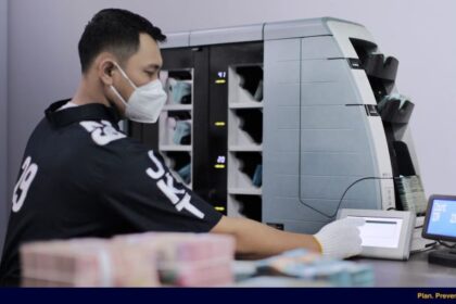 Petugas sedang melakukan pemeriksaan uang dengan menggunakan mesin. Foto: Ist