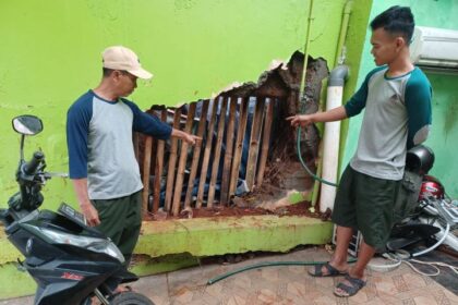 (Kiri-kanan) Kasiat, 56, dan Naril, 19, menunjukkan tembok Taman Pemakaman Umum (TPU) Cibubur II, RT 15/RW 05, Kelurahan Cibubur, Kecamatan Ciracas, Jakarta Timur, yang jebol pada Jumat (5/4) siang. Foto: Joesvicar Iqbal/ipol.id